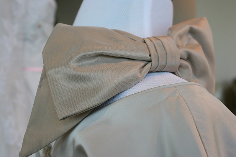 This bow sits on the shoulder/neckline of a dress.