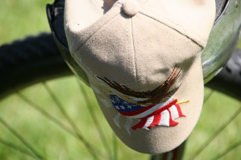 A patriotic cap hangs from a bicycle.