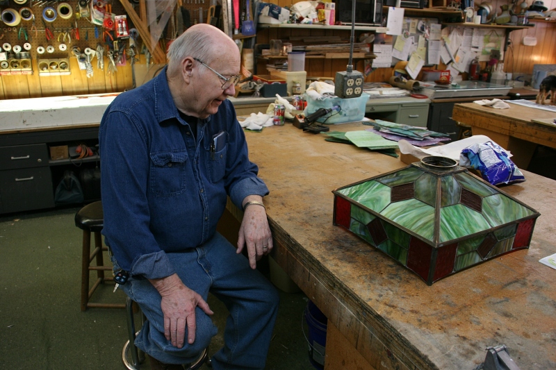 In his workshop, Mike talks to customers who've stopped by to pick up their restored light shade.