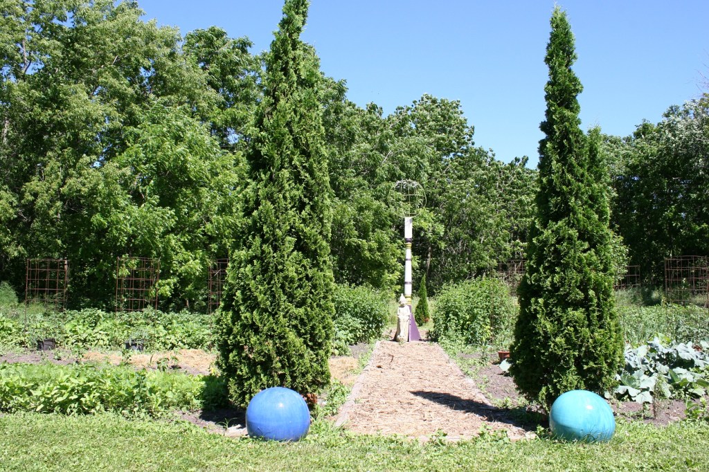 Shrub sculptures and art divide vegetable gardens.
