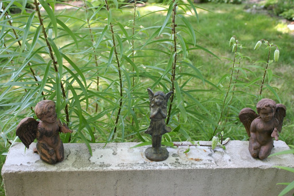 A sweet surprise of angels on a ledge next to lilies.