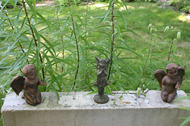 A sweet surprise of angels on a ledge next to lilies.