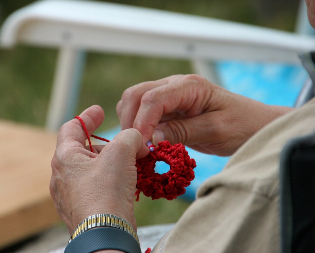 A fest goer crochets while musicians perform.