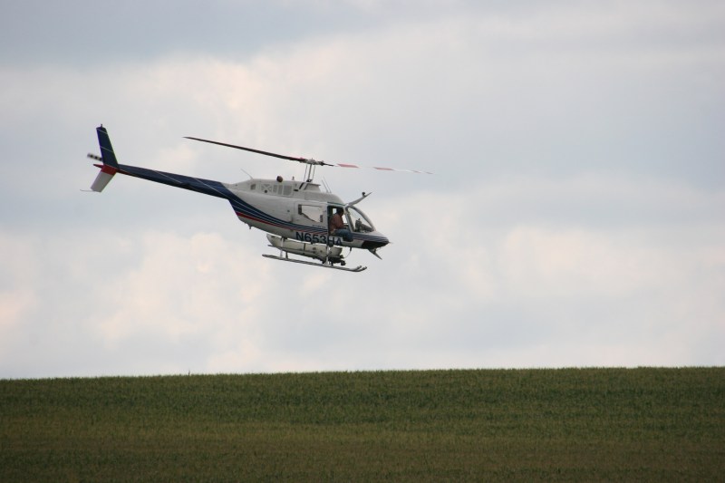 Helicopter spraying, 109 over corn field
