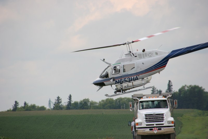 The helicopter lifts off from the mixing truck, ready for another round of spraying.