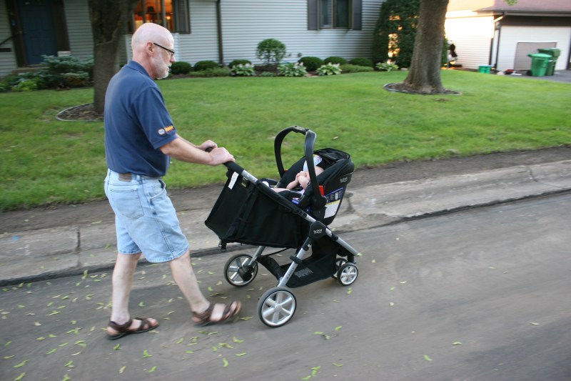 Grandpa pushes his little girl during an evening walk.