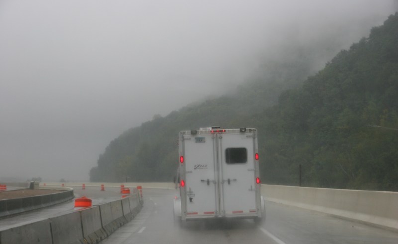 A vehicle travels along Interstate 90 near La Crosse in the rain Friday morning. Fog shrouds the bluffs in grey.