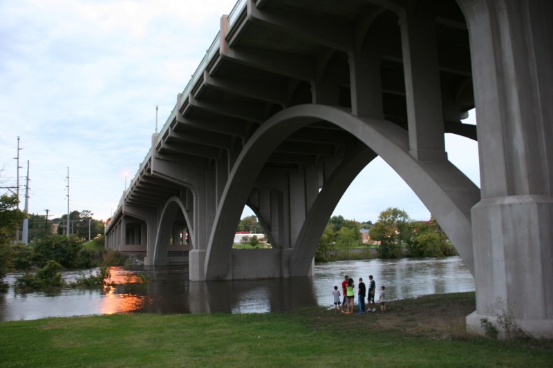 Locals are drawn under the viaduct that links the west and east side of Faribault during yet another flood in our community caused by excessive rainfall. Here the Straight River runs