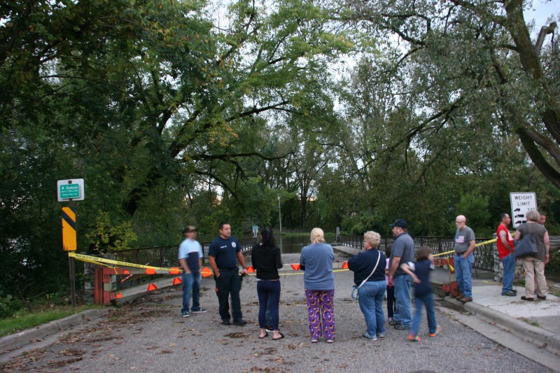 Onlookers gather at the bridge entry to Teepee Tonka Park, now flooded by the Straight River.