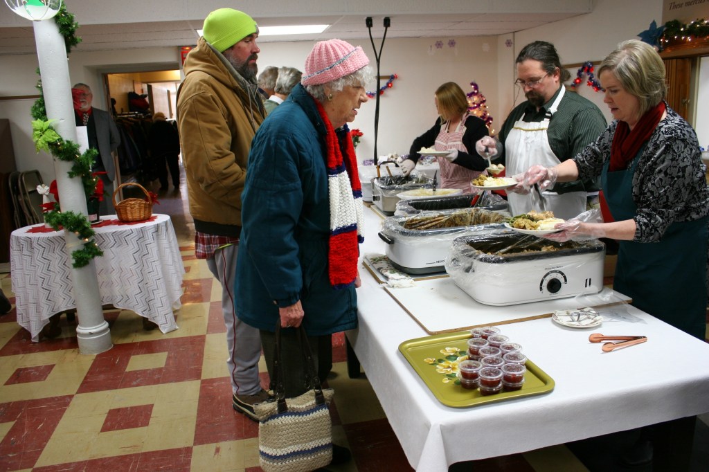 Volunteers plate a meal of turkey, mashed potatoes and gravy, stuffing, meatballs and green beans for diners. Additionally, cranberries and Christmas Cake were on the menu.