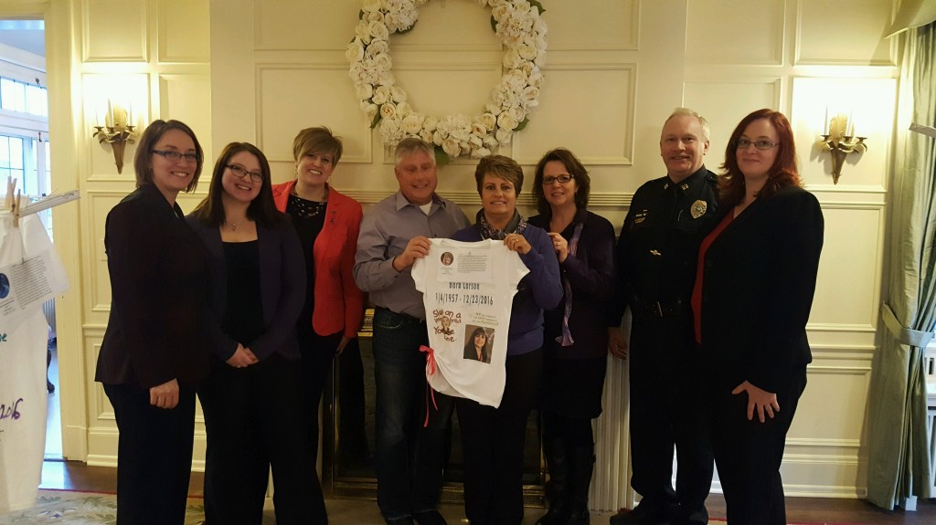 HOPE Center staffers and Faribault Police Department Captain Neal Pederson stand united with Barb Larson in honoring her memory. The family is holding the personalized t-shirt designed in Barb's memory for The Clothesline Project.