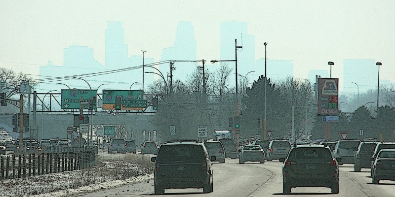 The outline of the Minneapolis skyline appears in the hazy distance while traveling along Minnesota State Highway 252.
