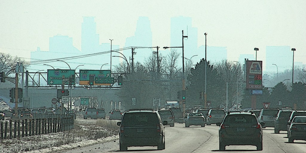 The outline of the Minneapolis skyline appears in the hazy distance while traveling along Minnesota State Highway 252.
