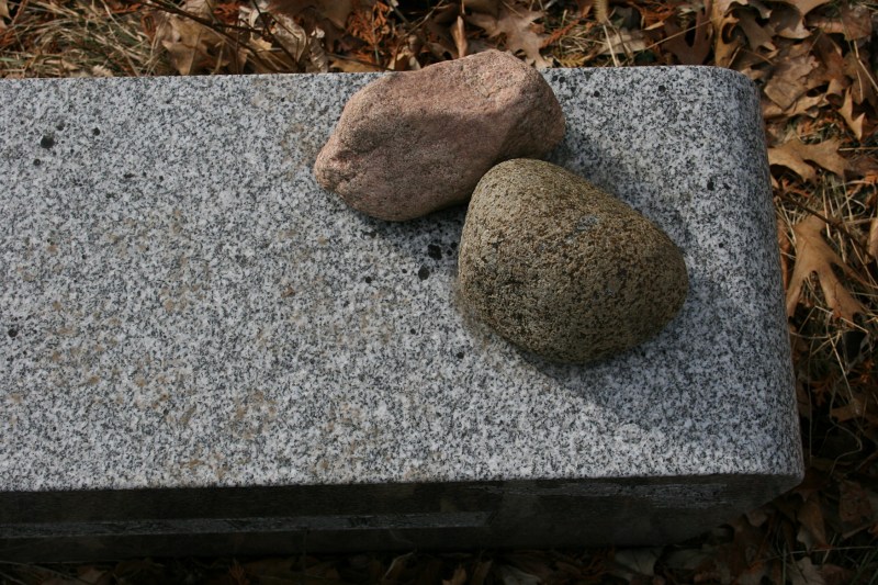 A Google search revealed that stones atop a headstone indicate a visitor stopped to pay respects to the deceased.