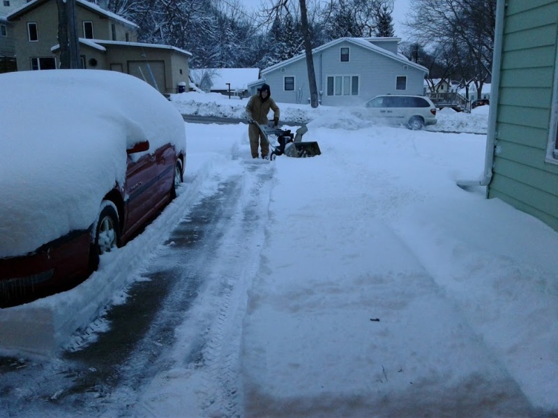 In the fading light of day, Randy works to blow snow from the driveway.
